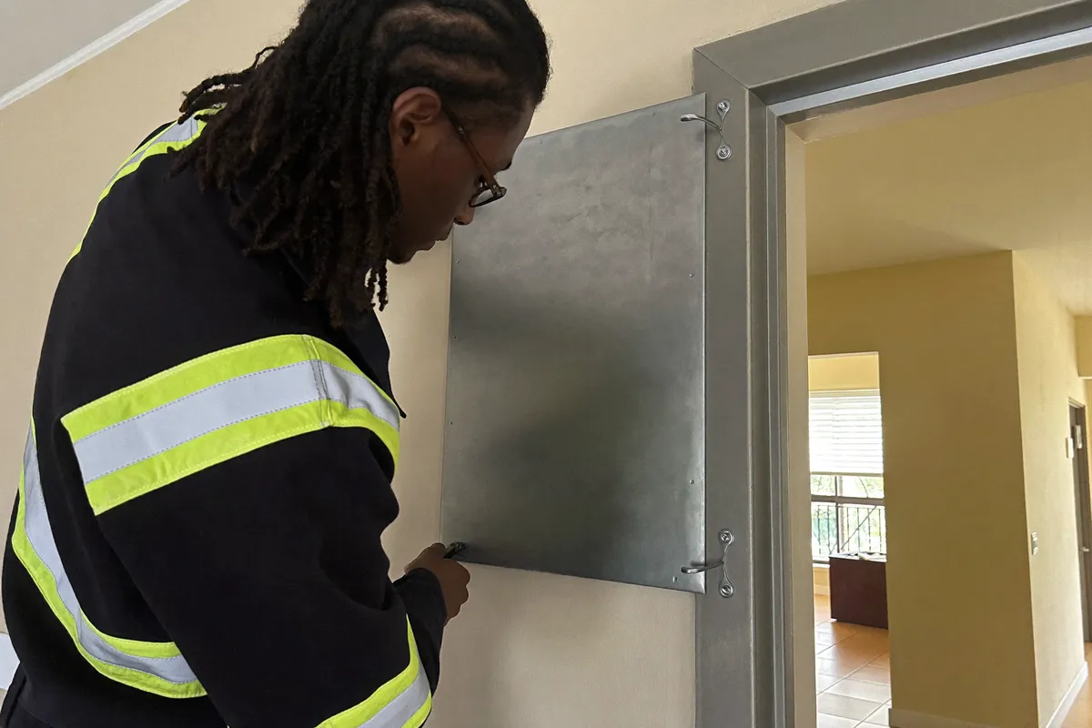 Instalador fijando un panel antiokupa de acero en el marco de la puerta de una vivienda